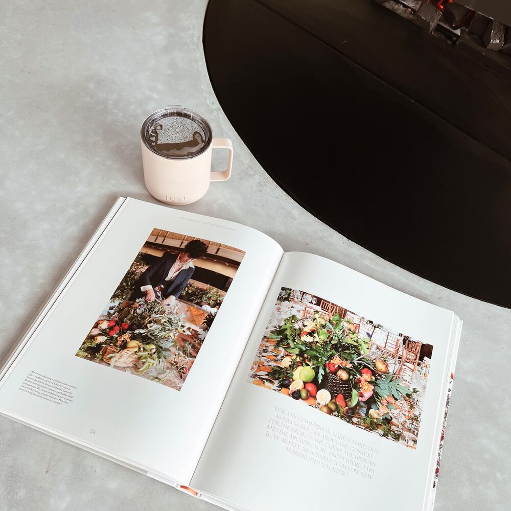 just bottle slow sip stainless steel insulated mug next to open book on marble table