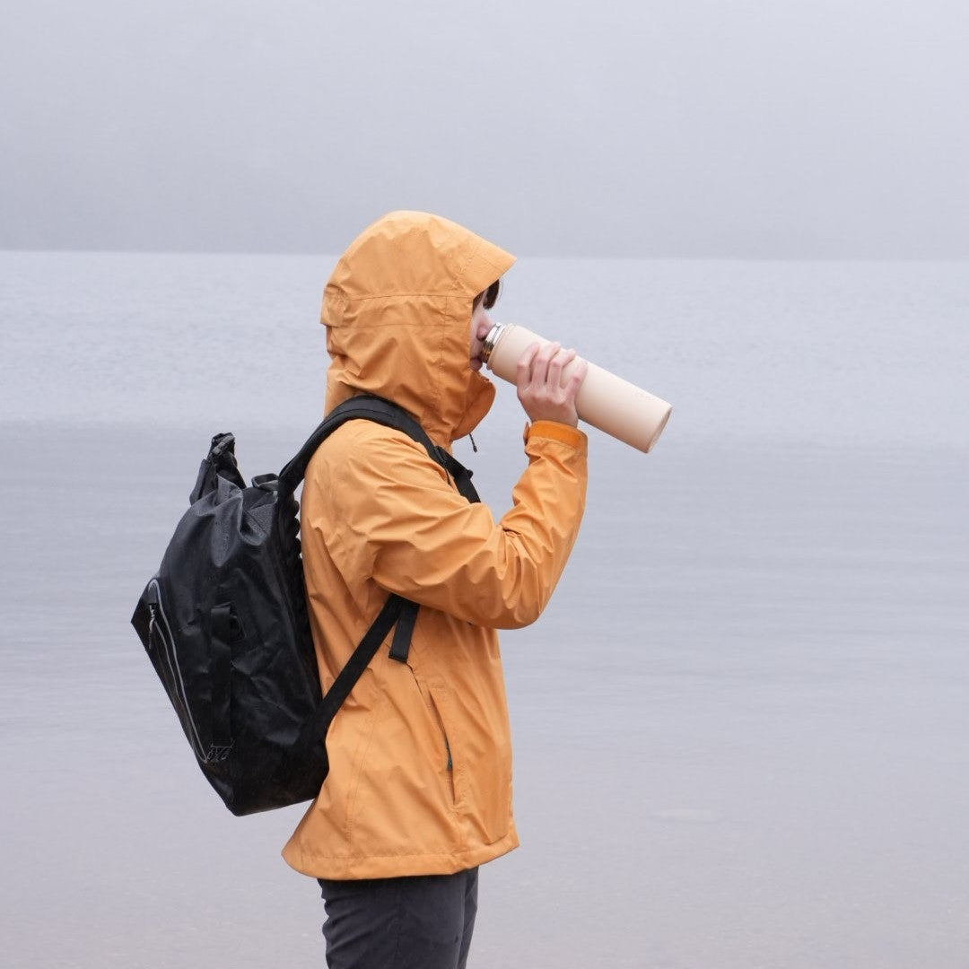 Women drink water from beige water bottle